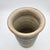 Hand-thrown stoneware vase with sgraffito scroll motif in a blue-gray glaze band, cream body, flared rim, and signed base.
