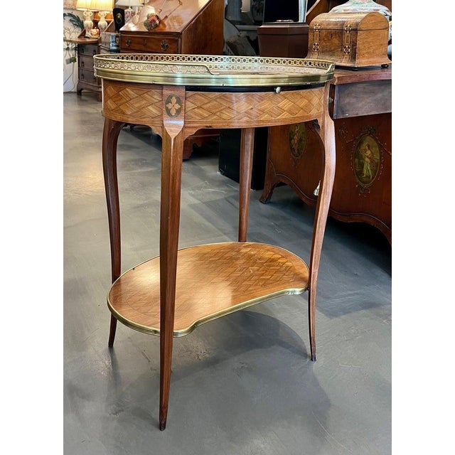 This is an elegant 19th century French Louis XV-style mahogany side table featuring exceptional marquetry throughout. The...