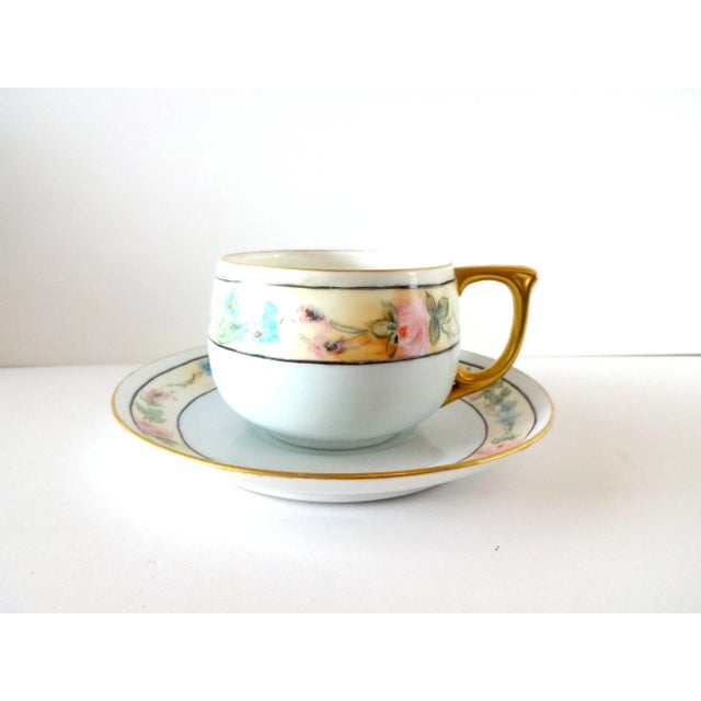 An antique teacup and saucer set, 1920s Art Deco, pale blue with black lines and golf gilt edges and handle, with bands of...
