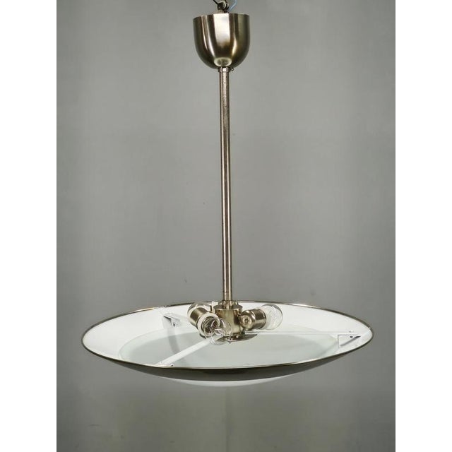 Elegant bauhaus pendant light produced in czechoslovakia during the 1930s, featuring a wide chrome-plated metal reflector...