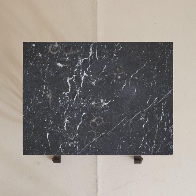 A French Art Deco occasional table from the 1940s, with a hand-hammered wrought iron base and black fossil marble top....