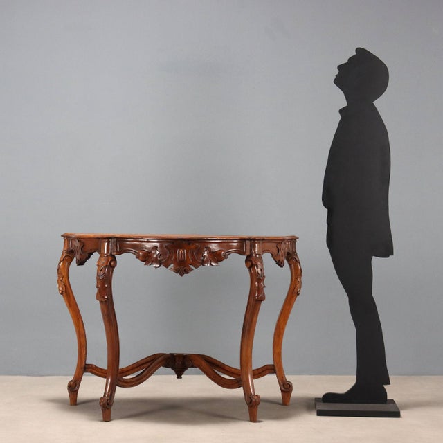 Louis Philippe walnut console table. Molded top, under-top band with carvings of three central coats of arms, and leafy...