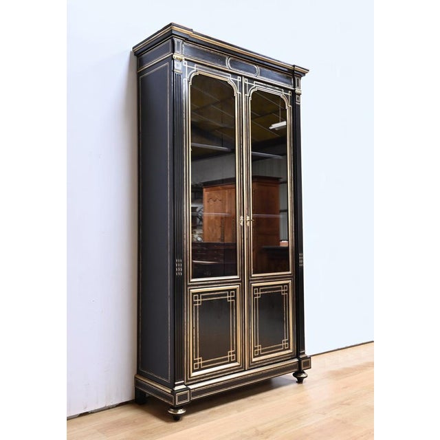 Important Napoleon III bookcase in blackened pear wood, opening with two doors, decorated with numerous brass inlays. Each...