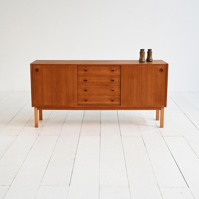 Teak and oak sideboard with sliding doors and a central drawer. Round carved handles. Scandinavian production, 1960s....