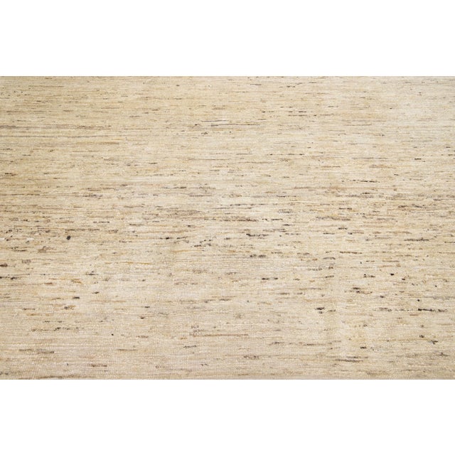 Beautiful modern Moroccan-style hand-knotted wool rug with a beige color field. This rug features a design in brown. This...