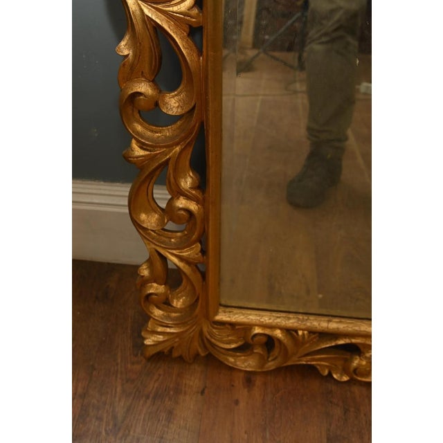 Italian giltwood wall mirror, beautifully hand carved in the Rococo manner with an elegant arched mirror plate set within...