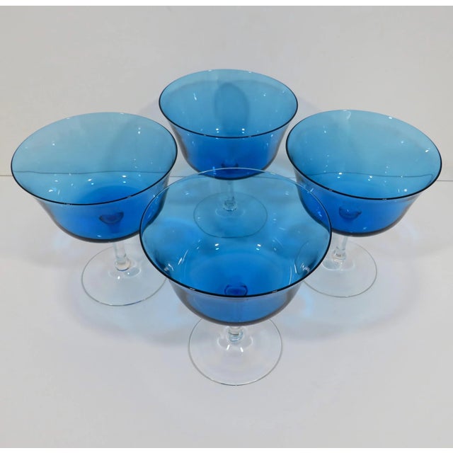 A set of mold-blown glass coupes in rich Mediterranean blue with flared rims, seated on clear stems. Dated to late 20th...