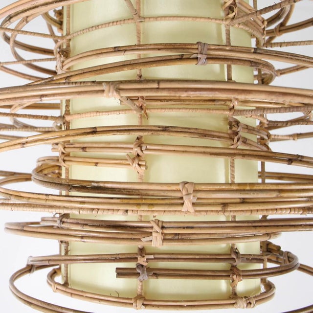 Stunning rattan and fabric pendant light. Made of expertly bent rattan and a central rattan cylinder that diffuses a...