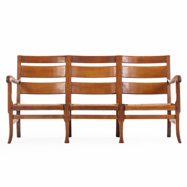 A charming French bench crafted in elm with horizontal slats, an open-arm design and traditional rush seats. The triple-...