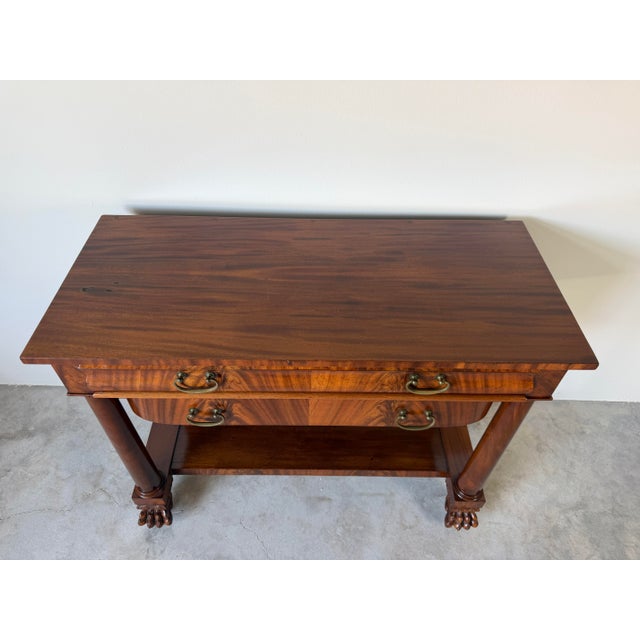 Elegant antique Empire-style console table featuring richly figured, two spacious drawers with brass bail pulls, classical...