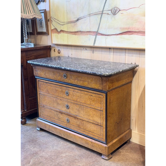 A distinguished antique French Louis Philippe commode showcasing exceptional burl walnut figuring and the restrained...