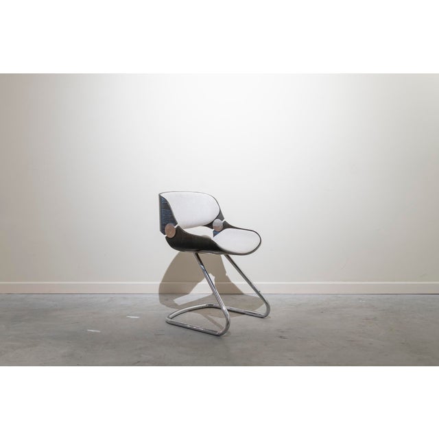 Set of four chairs with tubular steel legs and laminated wood seats and backs with upholstery. The chairs have been...