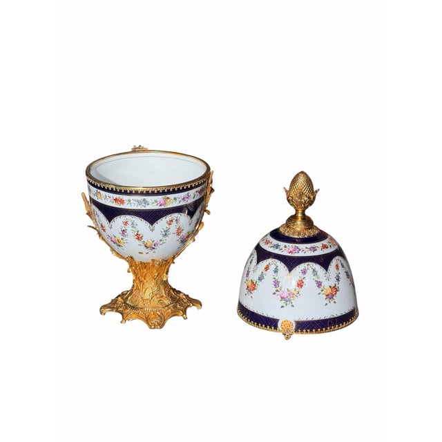 Oversized French-style porcelain egg-form jar featuring hand-painted floral bouquets, deep cobalt blue accents, and ornate...