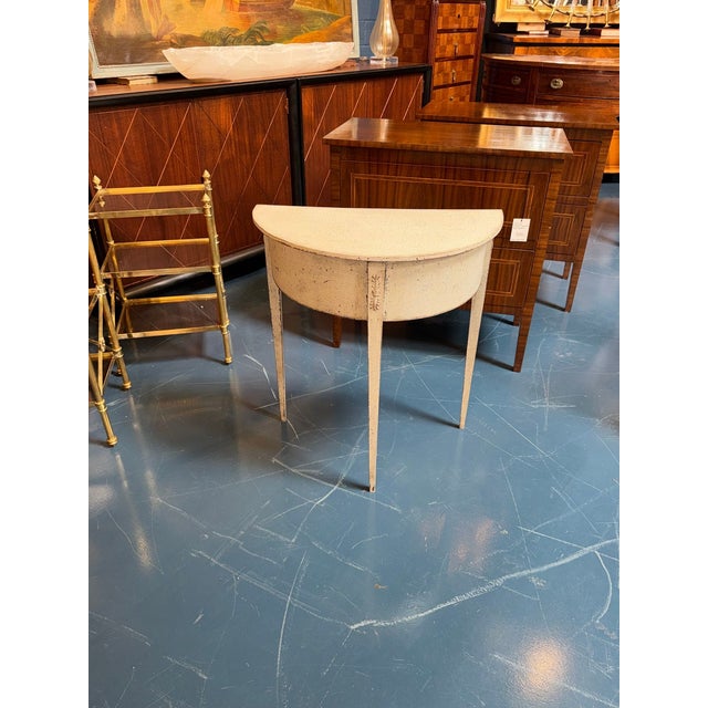 The Swedish Gustavian Painted Demi-Lune Side Table is an elegant and functional piece of furniture for any home. The...
