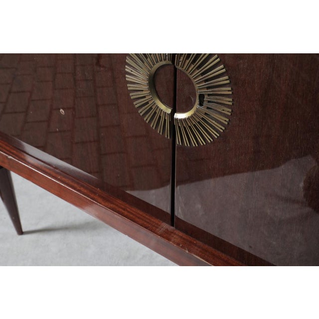 Sideboard with mahogany veneers and beautiful brass accents. Higly polished. Ring for front left leg can be taken from...
