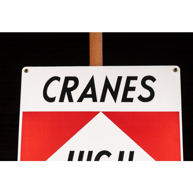 Porcelain-coated steel industrial safety sign reading "CRANES HIGH VOLTAGE HAZARD CHECK BOOM" with a bold upward...