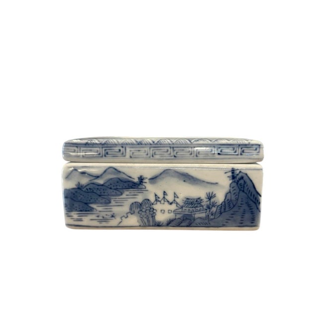 A lovely, Chinoiserie style ceramic box. Features hand painted Chinoiserie style scenic images in blue on a white ground....