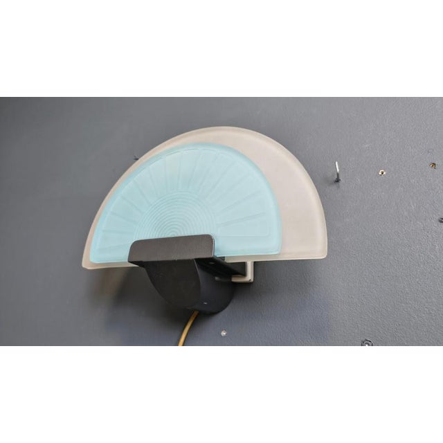 Glass wall sconce by Arteluce. The italian design wall lamp has a matte glass blue and white lamp shade and emit a soft...