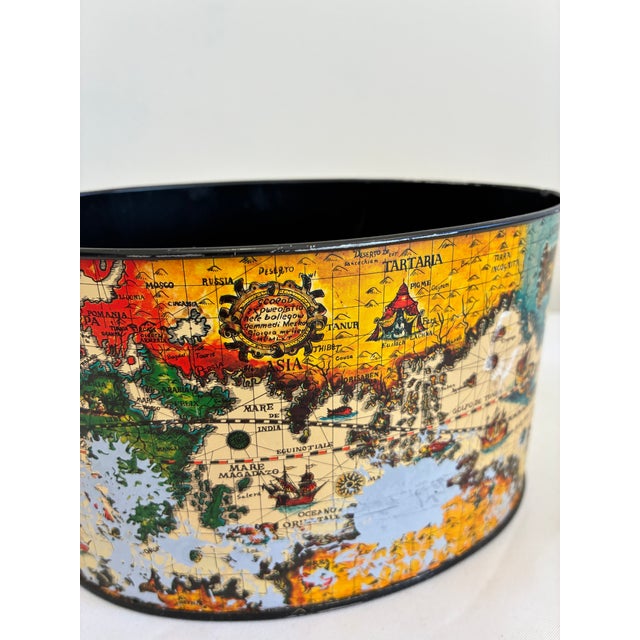 This vintage metal cachepot features a detailed antique-style world map design with rich coloration and old-world charm....