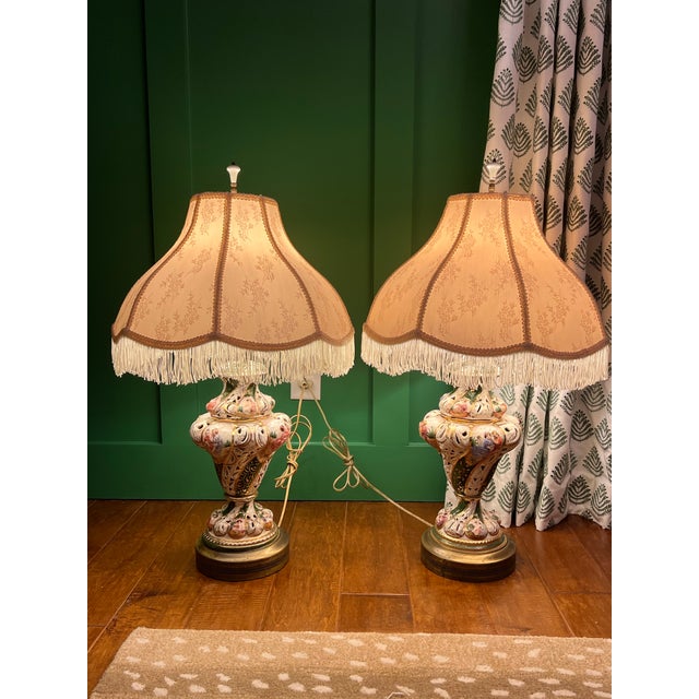 Pair of Capodimonte lamps with shades. Rich green stripes with gilt accents and pierced porcelain. Female figures are also...