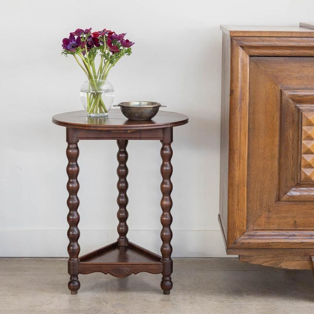 Lovely carved wood two-tier side table from France, 1940s. Circular top with triangular lower shelf and four carved bobbin...