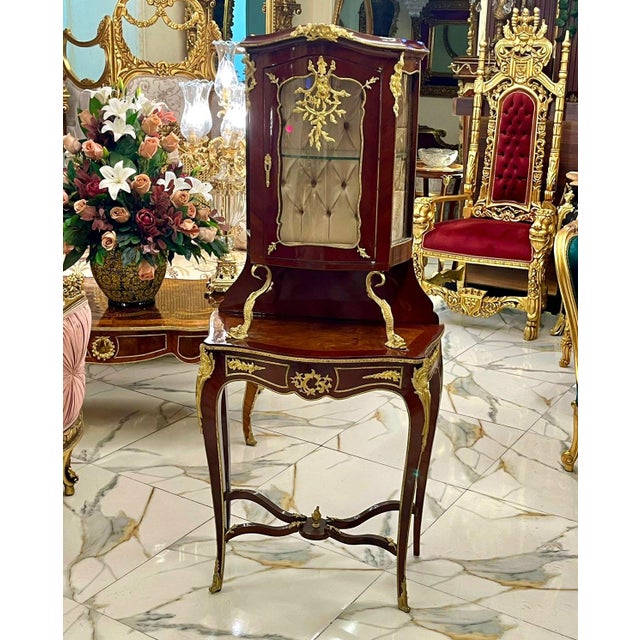 An exquisite French Louis XV style display cabinet featuring a beautifully crafted vitrine elevated on an elegant console...