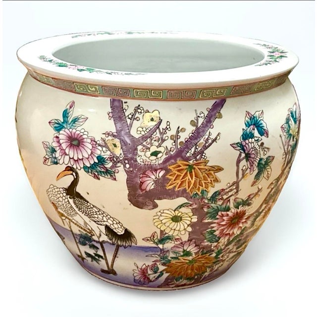 A vibrant hand‑painted famille‑rose fishbowl featuring colorful florals around the exterior and three lively koi swimming...
