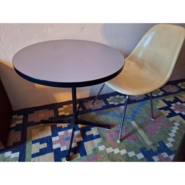 Charles and Ray Eames contract base bistro table with a light purple-grey circular top. The style of the label indicates a...