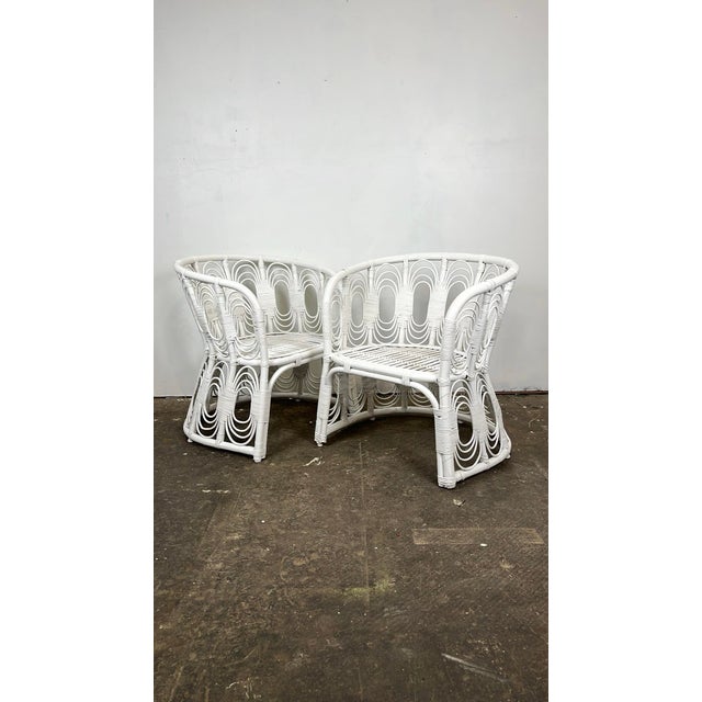 Vintage pair of rattan lounge chairs. Curved rattan frames with intricate looped pencil reed fretwork and cane wrapped...