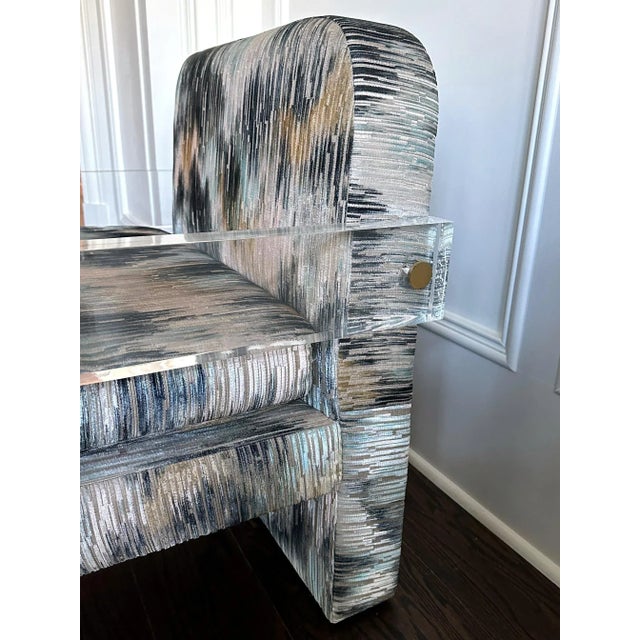 A lounge chair constructed in upholstered wood frame flanked by thick Lucite plank arm with exposed brass hardware, this...