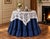 American Pacific 70" Ruffled Table Round with 36" x 36" Lace Accent Topper in navy blue and white, shown with original...