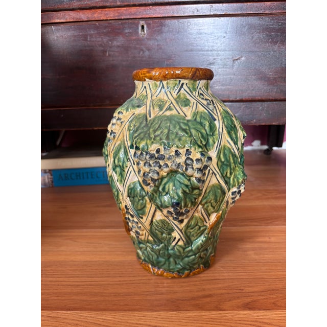This vase is a vintage Italian majolica pottery vase featuring a highly textured, three-dimensional grape vine, leaf, and...