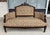 This antique Eastlake settee features a carved walnut frame with an arched upholstered back, shaped arms, turned front...