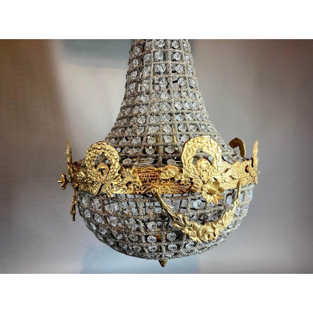A refined French Louis XVI–style chandelier dating from the 1960s, crafted in bronze with warm gilt detailing. Its...
