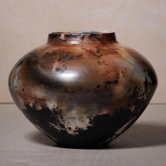 This raku vase by Craig Rigell features a bulbous, rounded shape with a narrow neck, showcasing an organic form that...