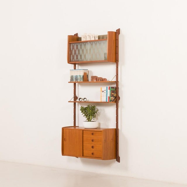 This fully renovated scandinavian teak wall unit comes from norway from the 1960s. It is a completely modular shelving...