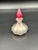 A beautifully crafted iridescent art glass perfume bottle featuring a scalloped, pearlescent base and a striking red...
