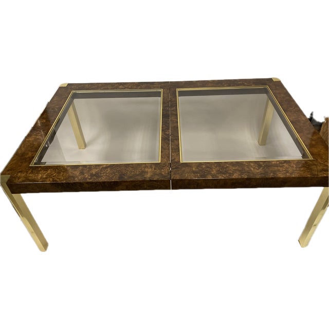 A striking vintage dining table, showcasing an elegant blend of luxurious burled walnut and inset glass panels. The richly...