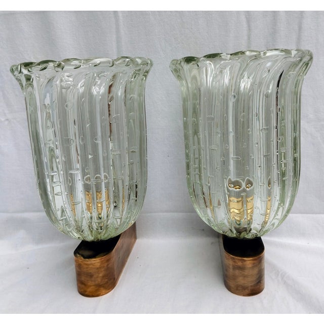 Pair of hand-blown and hand-crafted Murano glass wall lamps with a bulicante and straight edges. Natural brass frame with...