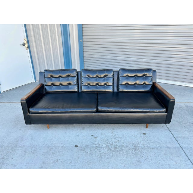 This mid-century walnut and vinyl sofa was designed and manufactured in the United States in the 1970s. This magnificent...