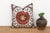 A large floral medallion in raised, hand-embroidered satin stitch anchors the center of this pillow — radiating palmette...