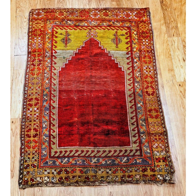 This beautiful Turkish area rug in a prayer rug patten features a magnificent abrash red color in the central field, a...