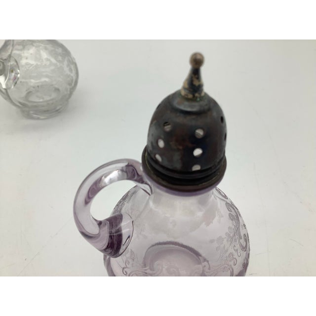 The salt and pepper shakers have a sterling silver top. The glass is a beautiful light, purple and clear glass body with...