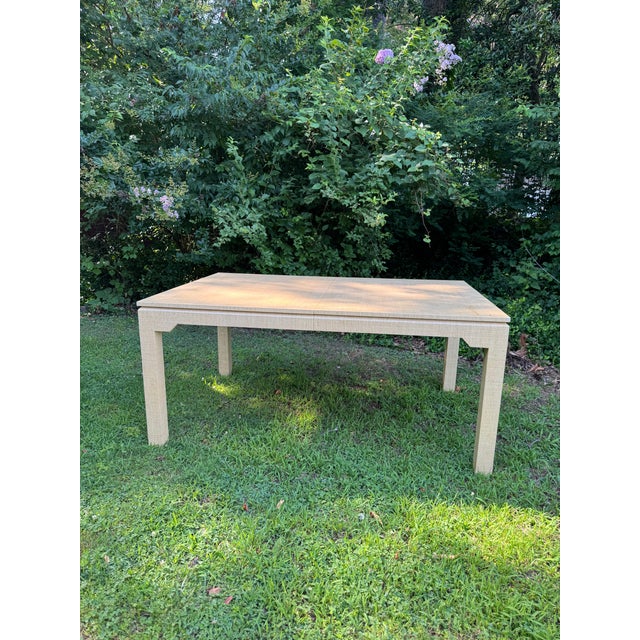 Vintage lacquered grasscloth dining table in a natural straw color. Beautiful parsons-style table comes with two leaves....