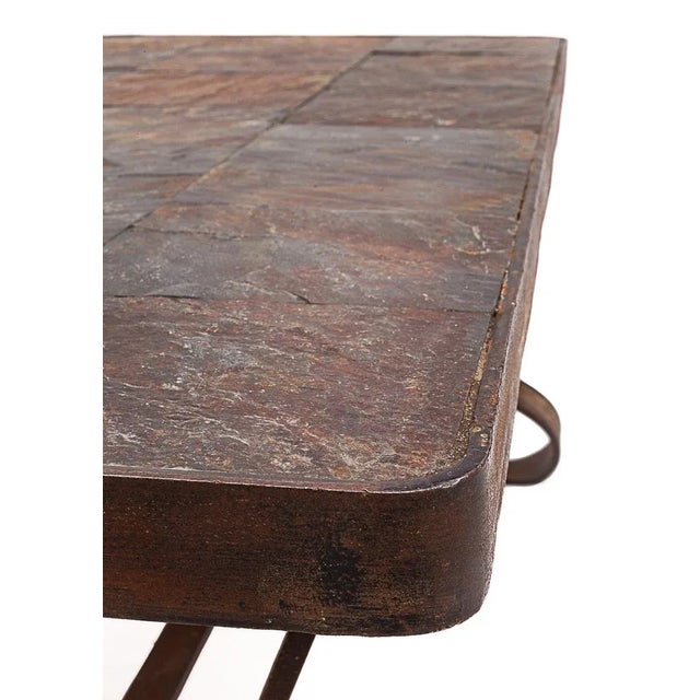 Brutalist coffee table by Jacques Adnet. Wrought iron base. Rough slate top. Circa 1950 This piece is attributed to the...