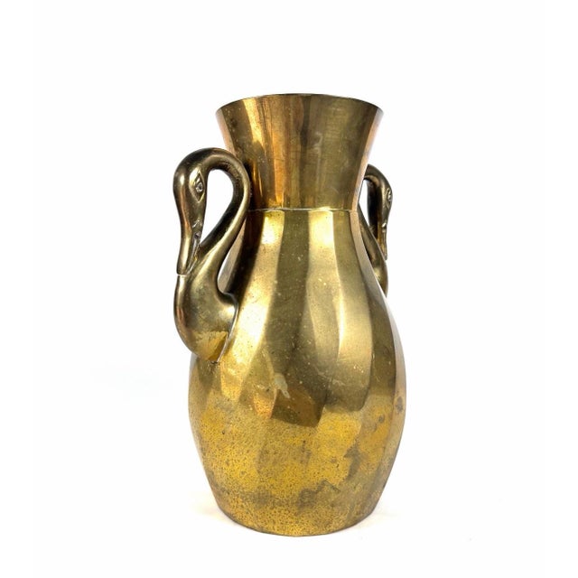 A vintage mid century brass vase with swan head handles. Good condition, with age spots and wear. It measures 9”h x 6.5”w.