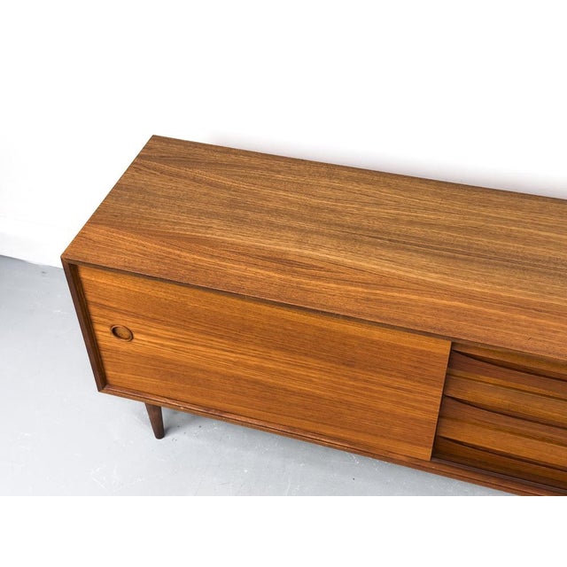 Perfectly proportioned, low teak sideboard with three drawers and a sliding door with a round recessed handle. One shelf...