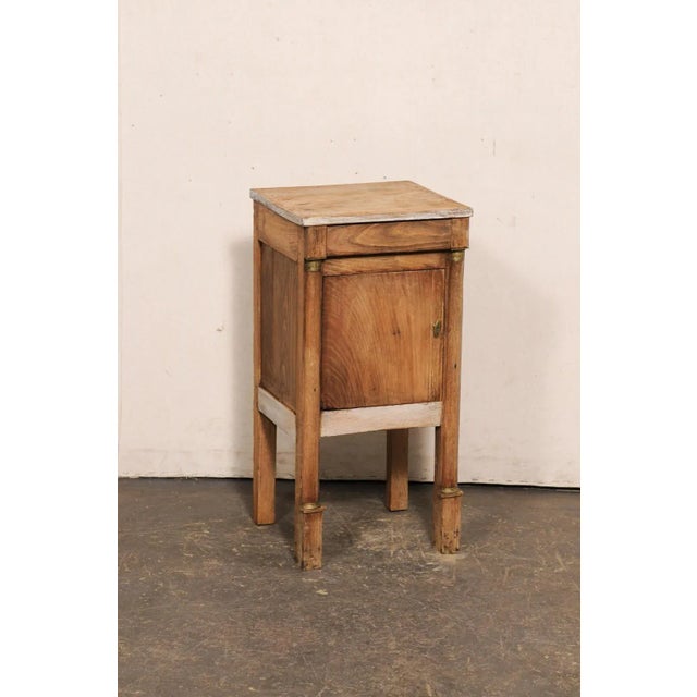 A French Neoclassical small-sized side chest, with brass accents, from the early 19th century. This antique Neoclassical...