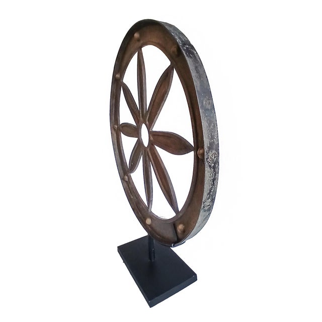 A wrought iron wagon wheel on stand. Indonesia, late 19th Century. Reclaimed from an old carriage, it has been preserved...