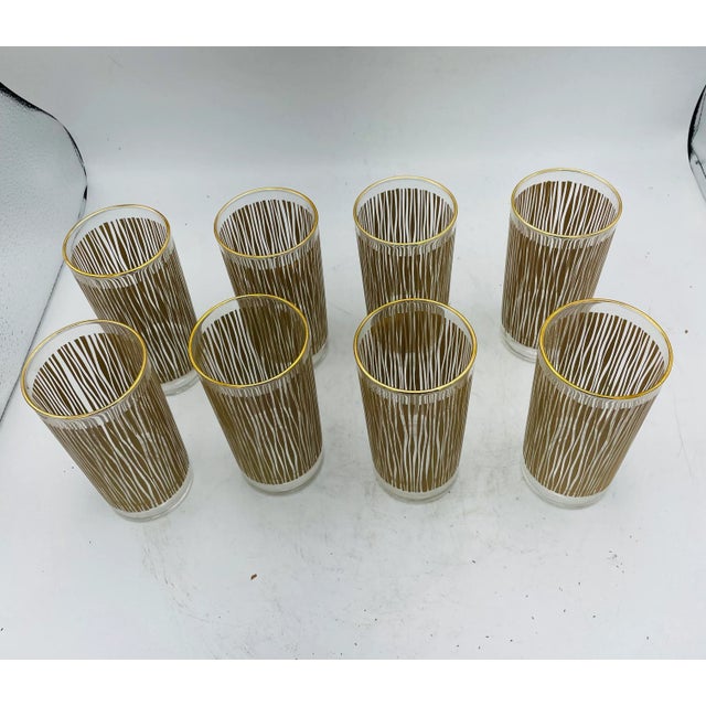 Unusual set of 8 Mid Century Modern Drinking Glasses. The lovely glasses have a gold silkscreen reed/wood design. A great...